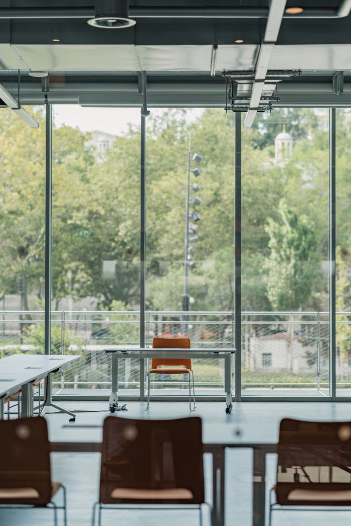 Spacious modern office with large windows overlooking green trees.